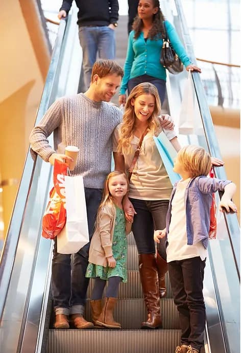 Image of smiling family on escalator in shopping mall